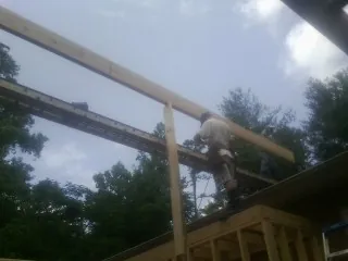 Carpenter setting a ridge beam over a new addition frame — Ice Dam Removal by Roofing Brothers in Pleasant Valley