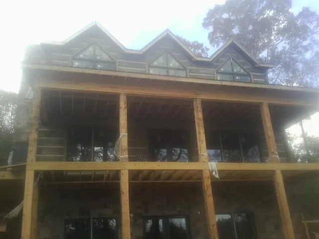 Dormers and porch framing on a large log home under construction — Roof Coating work by our crew in Pleasant Valley