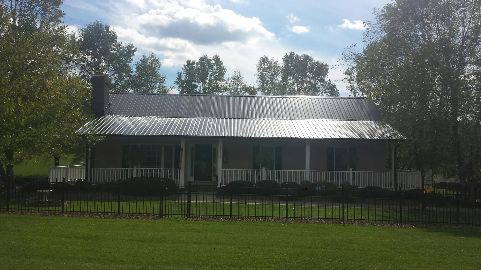 Gray metal roof on a brick ranch with a full width front porch — Gutter Guard Installation work by our crew in Pleasant Valley