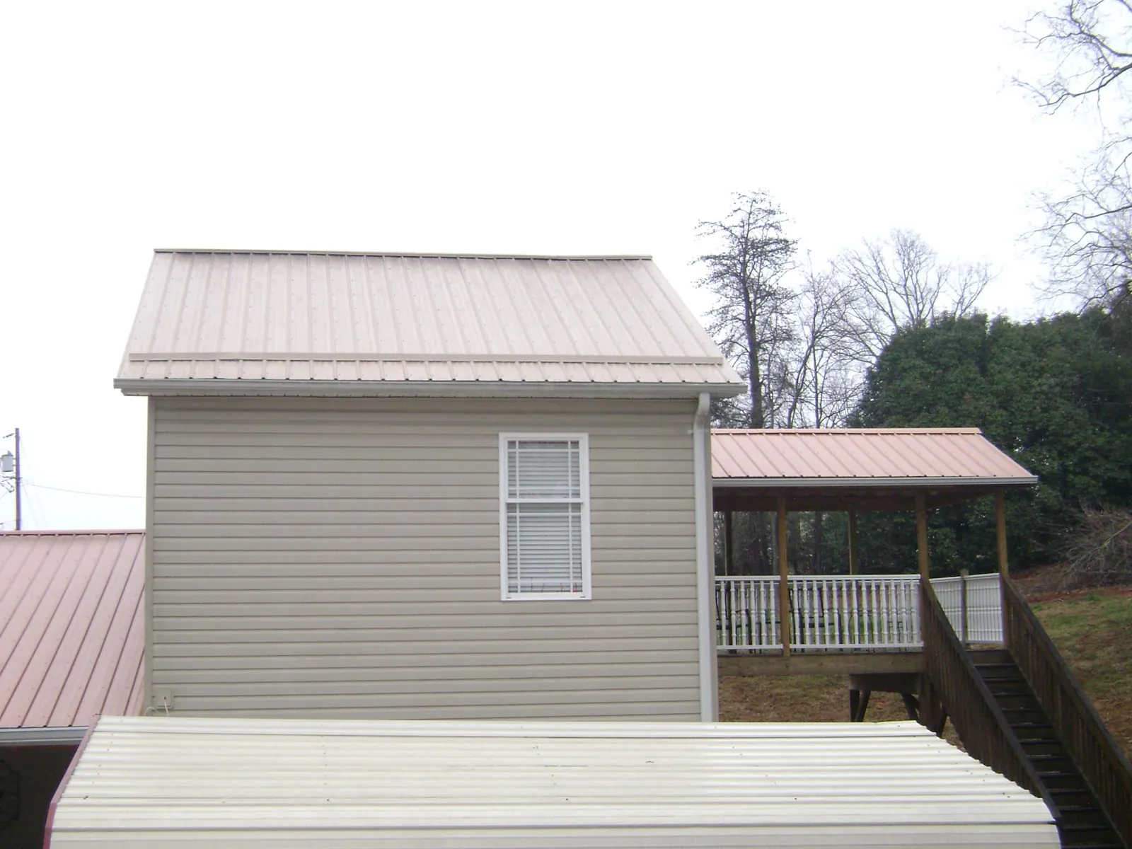 Tan metal roofs on a two story addition and attached porch, from a Roof Replacement job in Pleasant Valley